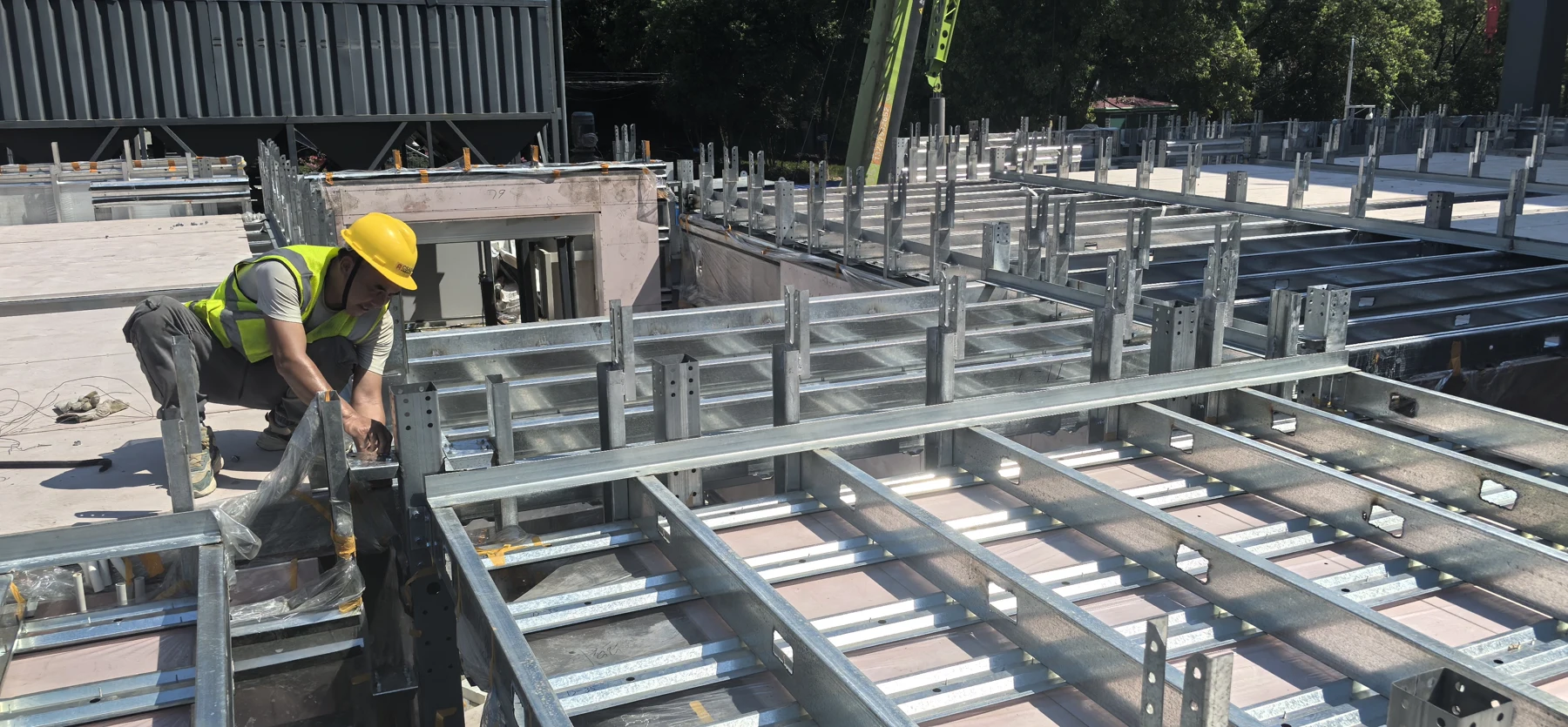 Actual on-site photograph of a worker assembling prefabricated steel floor components
